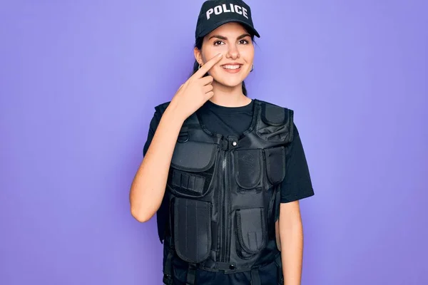 年轻的女警察身穿防弹背心制服 穿着紫色背景的制服 手指尖对着鼻子 笑容满面 美的概念 — 图库照片
