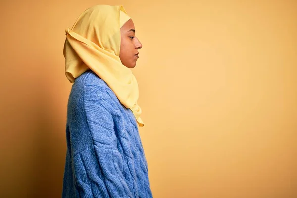 若いですアフリカ系アメリカ人女性身に着けていますムスリムヒジャーブ上の隔離された黄色の背景見ます側 リラックスしたプロフィールポーズとともに自然な顔とともに自信笑顔 — ストック写真