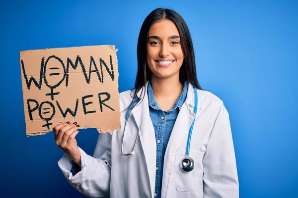 Young doctor woman wearing stethoscope holding cardboard banner with powe message with a happy face standing and smiling with a confident smile showing teeth