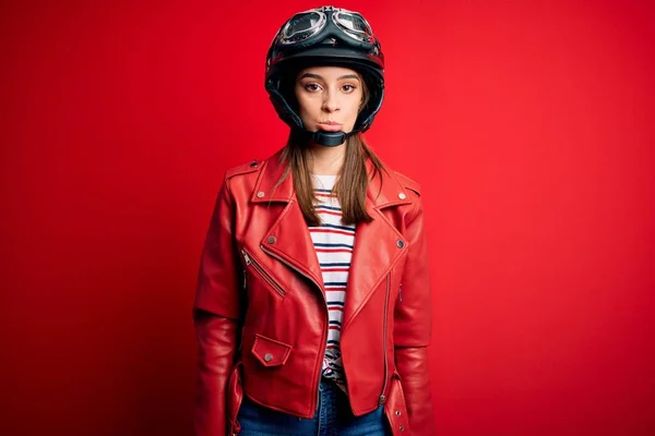若い美しいブルネットのオートバイのヘルメットと赤いジャケットを身に着けているオートバイの女性は落ち込んでおり 苦痛のために心配し 怒って恐れて泣いています 悲しい表情 — ストック写真