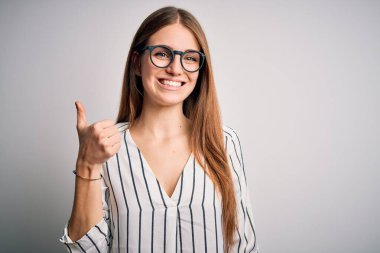 Genç, güzel, kızıl saçlı, sıradan çizgili tişört giyen ve gözlüklü bir kadın mutlu bir el hareketi yapıyor. Kameraya bakıp başarıyı gösteren ifade onaylanıyor.
