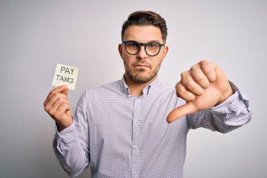 Mavi gözlü genç işadamı elinde vergi sözcüğünü tutan kızgın suratlı, olumsuz işaretli baş parmakları aşağıda, reddedilme kavramlı.