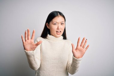 Genç ve güzel Asyalı bir kadın izole edilmiş arka planda dikilmiş korku ifadesinden korkmuş ve dehşete düşmüş halde duruyor. El hareketlerini durdur, şok içinde bağır. Panik konsepti.