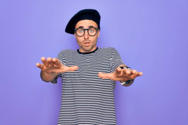 Mor arka planda mavi gözlü, çizgili tişört ve Fransız beresi giyen yakışıklı bir adam. Avuçlarıyla hareket etmeyi kesiyor. Öfkeli ve hüsran dolu bir ifade.