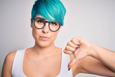 Mavi saçlı, sıradan tişörtlü, kızgın yüzlü gözlüklü, negatif işaretli, baş parmakları aşağıda, reddedilme kavramından hoşlanmayan genç ve güzel bir kadın.