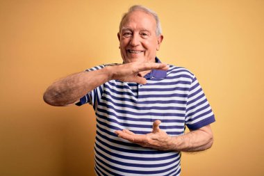 Gri saçlı, donanma çizgili tişört giyen, sarı arka planda duran, büyük ve büyük beden işareti olan, ölçü sembolü olan gri saçlı bir adam. Kameraya bakıp gülümsüyor. Ölçüm konsepti.