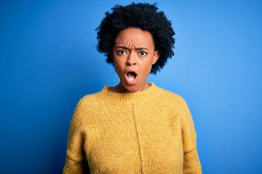 Kıvırcık saçlı, sarı kazaklı, genç, Afro-Amerikan kadın. Şok olmuş, şüpheci, alaycı, ağzı açık ve şaşırmış görünüyor.