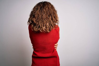 Orta yaşlı esmer kadın izole edilmiş beyaz arka planda dikilip mutlu ve pozitif bir şekilde kendine sarılıyor. Sevgi ve özgüven.