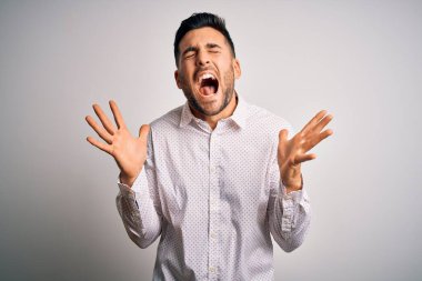 Zarif gömlekli genç adam, izole edilmiş beyaz arka planda duruyor. Kollarını kaldırmış, gözlerini kapatmış heyecanla haykırarak başarının çılgınlığını kutluyor. Kazanan konsept