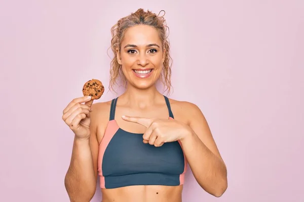 Joven Hermosa Rubia Deportista Haciendo Deporte Sosteniendo Galleta Sobre Fondo — Foto de Stock