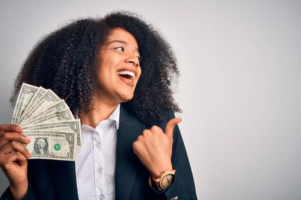 現金の紙幣を持っているアフロの髪を持つ若いアフリカ系アメリカ人のビジネス女性ポイントと笑顔で親指で側面まで示す — ストック写真