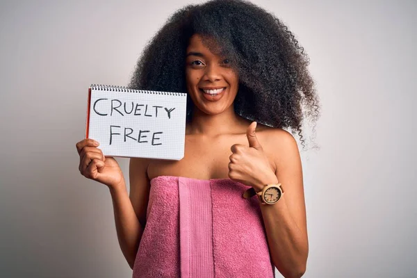 Young african american woman with afro hair wearing a towel asking for cruelty free beauty happy with big smile doing ok sign, thumb up with fingers, excellent sign