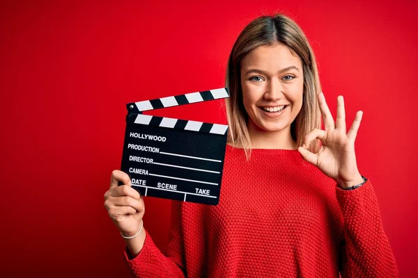 Młoda Piękna Kobieta Trzyma Clapboard Stojąc Nad Odizolowanym Czerwonym Tle — Zdjęcie stockowe