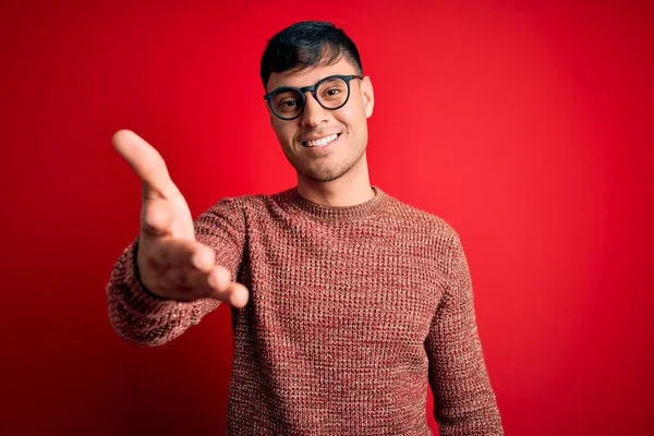 Mladý Pohledný Hispánec Šprtských Brýlích Červeném Pozadí Přátelsky Usmívá Nabízí — Stock fotografie