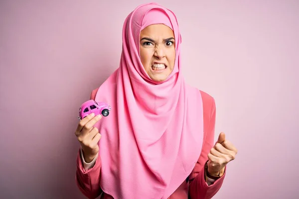Молодая Девушка Мусульманском Хиджабе Держит Маленькую Игрушку Автомобиля Изолированном Розовом — стоковое фото