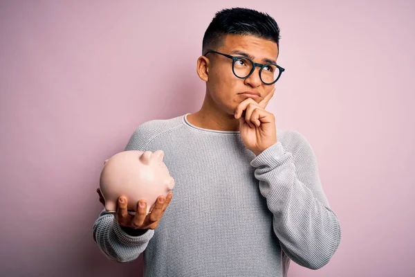 Hombre Latino Guapo Joven Sosteniendo Alcancía Sobre Fondo Rosa Aislado —  Fotos de Stock