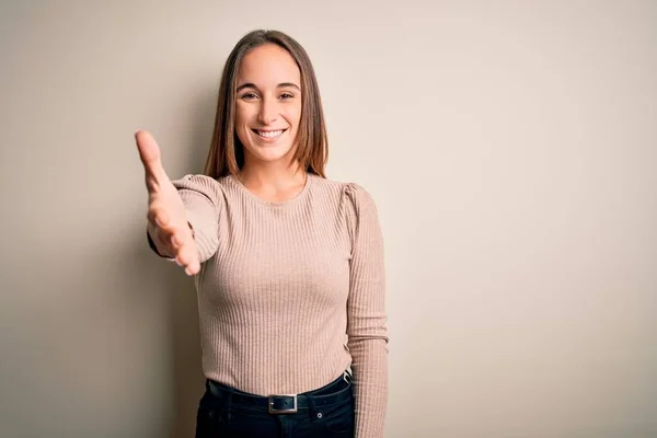 年轻美丽的女人穿着休闲装 站在孤独的白色背景上 微笑友好地握手致意和欢迎 成功的业务 — 图库照片