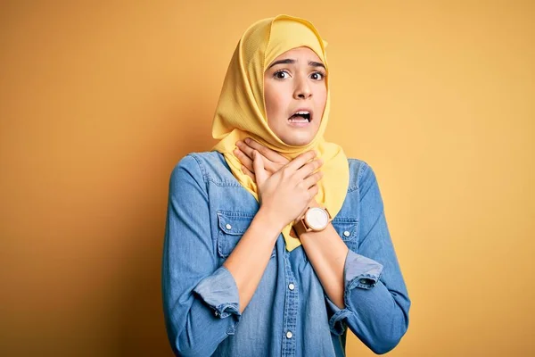 年轻美丽的女孩头戴穆斯林头巾 站在孤立的黄色背景上喊叫着 因为痛苦的窒息而窒息 健康问题 窒息和自杀的概念 — 图库照片