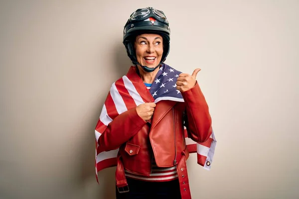 骑摩托车的中年妇女头戴摩托车头盔 手拿着美国国旗 高高兴兴地朝旁边看去 — 图库照片