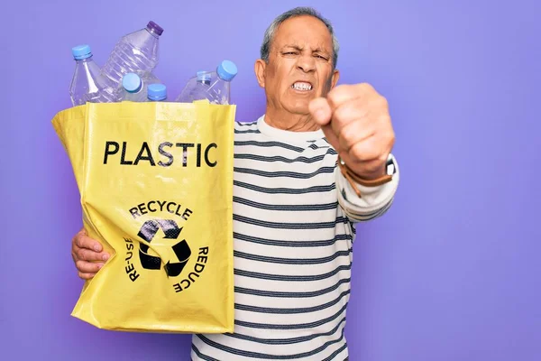 Senior Człowiek Recyklingu Torba Plastikowych Butelek Recyklingu Fioletowym Tle Zirytowany — Zdjęcie stockowe