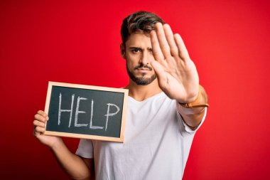 Elinde tahtayla kırmızı bakterinin üzerinden yardım mesajı tutan genç adam dur işareti yapıyor ciddi ve kendinden emin bir ifadeyle, savunma jesti yapıyor.