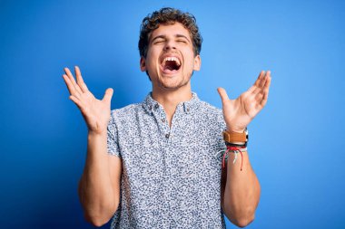 Sarışın, tatilde, kıvırcık saçlı, sıradan polo giyen, başarı için deli ve deli olan genç, kolları havada ve gözleri kapalı heyecanlı bir şekilde kutlama yapan yakışıklı bir adam. Kazanan konsept