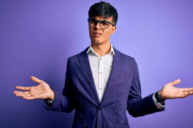 Ceket ve gözlük takan genç yakışıklı iş adamı. Mor arka plandan habersiz ve kolları açık, hiçbir fikri yok..