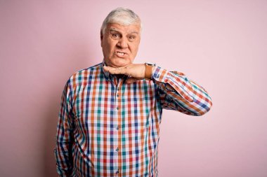 Üst düzey yakışıklı beyaz gömlekli, soyutlanmış pembe arka planda, boğazını bıçak gibi kesen, saldırganlığı şiddetle tehdit eden biri.