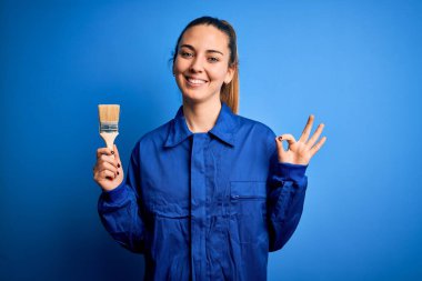 Mavi gözlü genç bir ressam. Üniforma giyiyor. Boya fırçası kullanıyor.