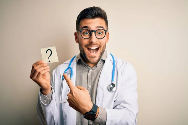 Młody Lekarz Nosi Stetoskop Trzymając Przypomnienie Znaku Zapytania Odosobnionym Tle — Zdjęcie stockowe