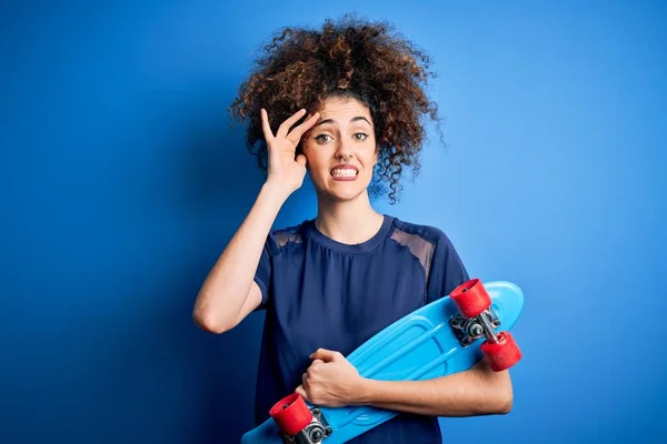 Jonge Sportieve Vrouw Met Krullend Haar Piercing Schaatsen Blauwe Achtergrond — Stockfoto