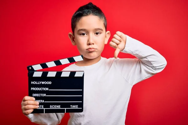 若いです男の子撮影ビデオを保持映画監督Clapboard上の隔離された赤の背景とともに怒っている顔 負のサインショー嫌いとともに親指ダウン 拒否の概念 — ストック写真
