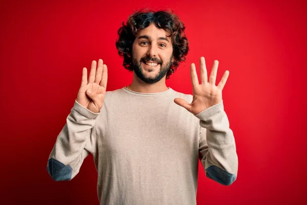年轻英俊的男子留着胡子 身穿休闲装 站在红色的背景上 用9号手指指尖 面带微笑 自信而快乐 — 图库照片