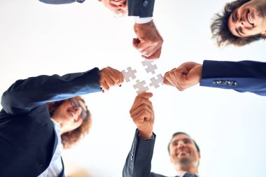 Group of business workers smiling happy and confident. Standing on a circle with smile on face trying to connect puzzle pieces at the office.