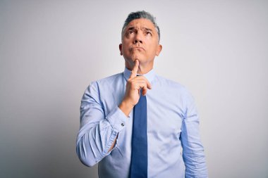 Orta yaşlı, yakışıklı, gri saçlı, şık gömlekli, kravatlı bir iş adamı. Kuşkuya odaklanmış, parmakları çenesinde ve yukarı bakıyor.