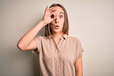 İzole edilmiş beyaz arka plan üzerinde sıradan bir tişört giyen genç güzel bir kadın şaşırmış yüz ve gözleriyle parmaklarından içeri bakan bir jest yapıyor. İnançsız ifade.