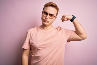 Genç, yakışıklı, günlük tişört giyen, pembe arka planda duran, güçlü, kendinden emin ve gururlu bir adam.