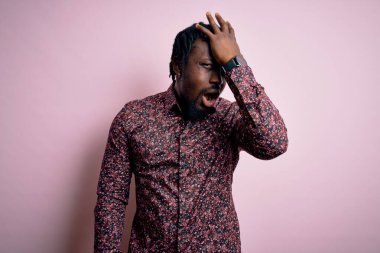 Genç, yakışıklı, Afro-Amerikan bir adam pembe arka planda dikilmiş, yanlışlıkla el ele tutuşarak şaşırmış, hatayı hatırla. Unuttum, kötü hafıza konsepti.