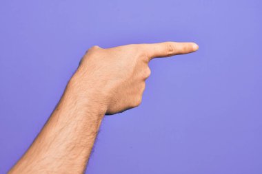 İzole edilmiş mor arka plan üzerinde parmaklarını gösteren beyaz bir gencin eli işaret parmağıyla kenarı işaret ediyor ve bir seçim yapıyor.