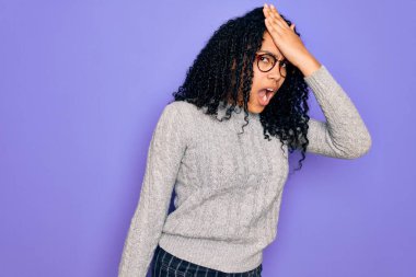 Genç Afro-Amerikalı kadın, mor arka plan üzerine gündelik süveter ve gözlük takıyor. Yanlışlıkla el ele tutuşarak şaşırdı. Hatayı unutmayın. Unuttum, kötü hafıza konsepti.