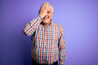 Kıdemli yakışıklı, beyaz gömlekli, tek gözü mor, yüzünde kendine güvenen bir gülümseme ve sürpriz bir duygu ile donatılmış bir mor arka plan..