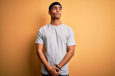 Yakışıklı Afro-Amerikan sporcu sarı arka planda spor giysisi giyiyor. Gülümsüyor ve başka tarafa bakıyor..