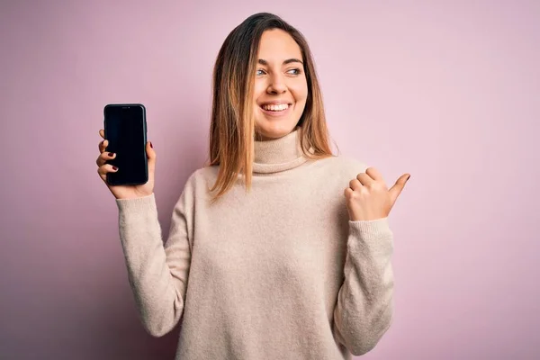 Młoda Piękna Brunetka Trzyma Smartfon Pokazując Ekran Różowym Tle Wskazując — Zdjęcie stockowe