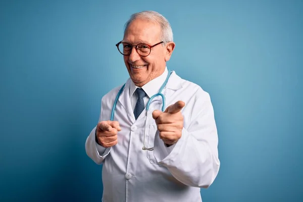 Starszy Siwy Lekarz Noszący Stetoskop Płaszcz Medyczny Niebieskim Tle Wskazujący — Zdjęcie stockowe