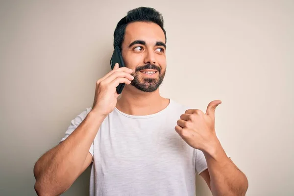 Молодой Красавчик Бородой Разговаривает Смартфону Показывая Пальцем Вверх Сторону Счастливым — стоковое фото