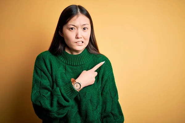 녹색의 스웨터를 배경에 아름다운 아시아 여인은 손가락을 걱정하고 걱정하며 표정을 — 스톡 사진