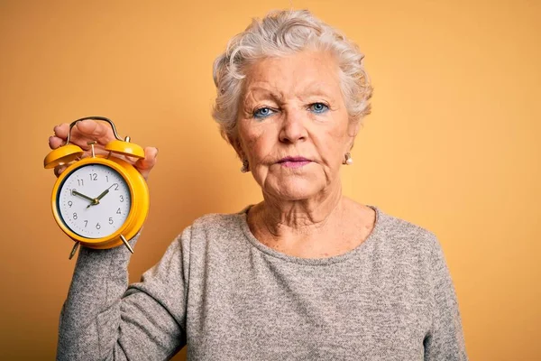 Senior Krásná Žena Drží Budík Stojí Nad Izolované Žluté Pozadí — Stock fotografie