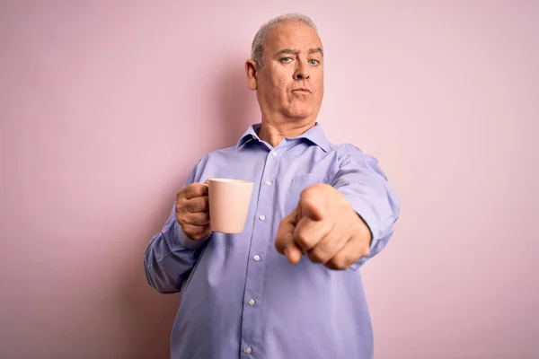 中年ハンサムな角質男飲むコーヒーのマグカップの上に隔離されたピンクの背景指摘で指でカメラとあなたに 手のサイン 正と自信を持ってジェスチャーからフロント — ストック写真