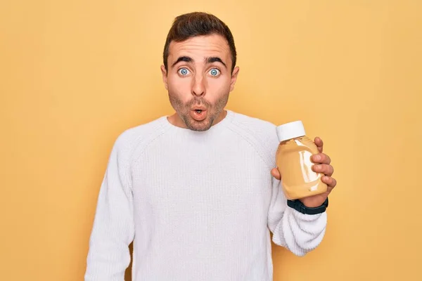 Junger Gutaussehender Mann Der Eine Flasche Senfsauce Über Gelbem Hintergrund — Stockfoto