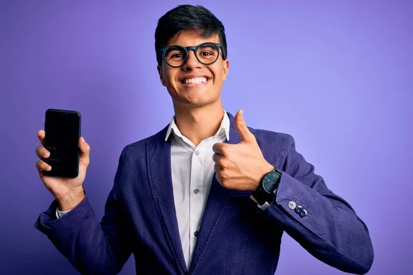 Mladý Pohledný Obchodník Bundě Brýlích Drží Smartphone Ukazuje Obrazovku Šťastný — Stock fotografie
